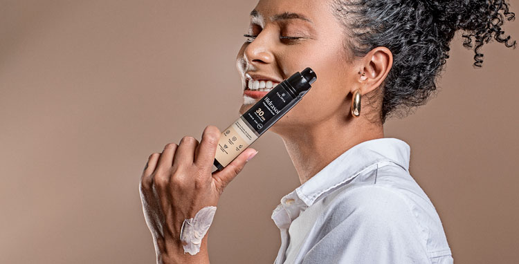 Mulher negra sorrindo, segurando o protetor solar na mão. Textura do protetor solar na mão.